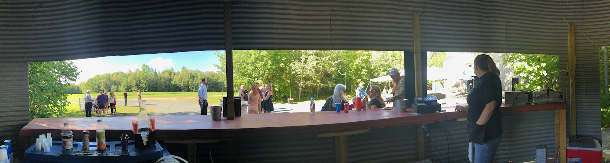Wide angle image of an outdoor bar setting with customers engaging in conversation outside on a sunny day